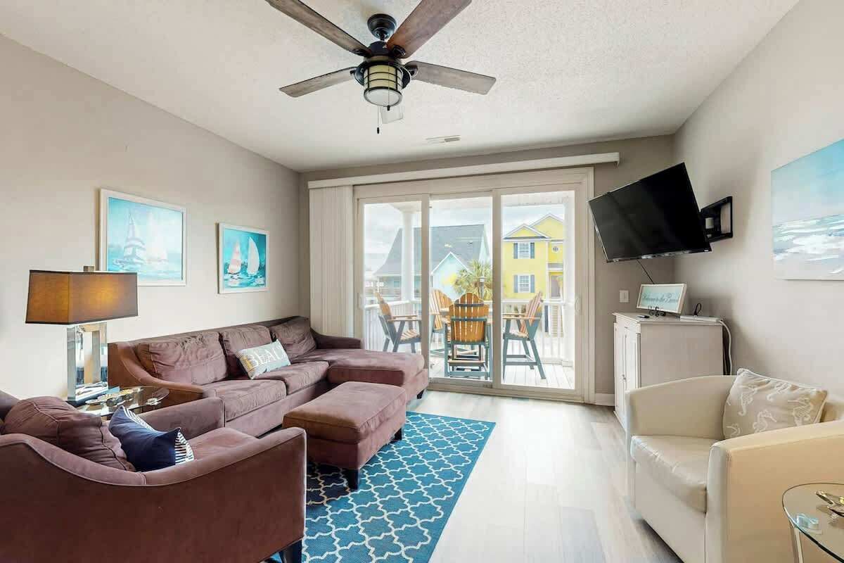 A living room with a sofa, ottoman, and a television mounted on the wall.