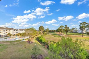 A golf course with a clubhouse and residential buildings in the background. - Beach at the Greens Retreat (Myrtle Beach)