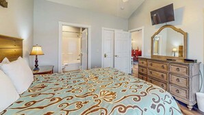 Ein Schlafzimmer mit einem Bett, einem Schminktisch, einem Fernseher und einem Deckenventilator.