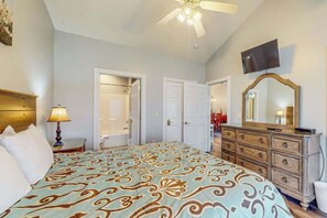 Ein Schlafzimmer mit einem Bett, einem Schminktisch, einem Fernseher und einem Deckenventilator.