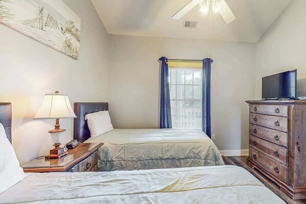 A hotel room with two beds, a television, a dresser, and a painting on the wall. - Beach at the Greens Retreat (Myrtle Beach)