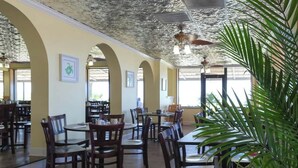 A restaurant interior with wooden tables and chairs, a ceiling with a textured pattern, and framed artwork on the walls. - Sand Dunes North Tower #1510 (Myrtle Beach)