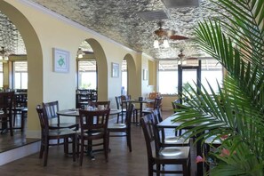 A restaurant interior with wooden tables and chairs, a ceiling with a textured pattern, and framed artwork on the walls. - Sand Dunes North Tower #1510 (Myrtle Beach)