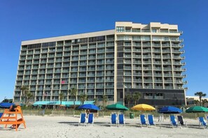 A multi-story hotel with a uniform facade, numerous balconies, and a beachside location with sun loungers and umbrellas. - Sand Dunes North Tower #1510 (Myrtle Beach)