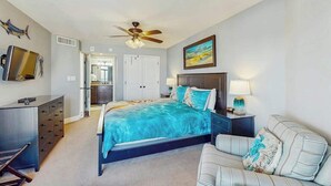 A bedroom with a bed, a desk, a chair, a ceiling fan, and a painting on the wall. - Sand Dunes North Tower #1510 (Myrtle Beach)