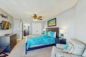 A bedroom with a bed, a desk, a chair, a ceiling fan, and a painting on the wall. - Sand Dunes North Tower #1510 (Myrtle Beach)