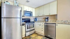 A kitchen with stainless steel appliances, including a refrigerator, microwave, stove, and dishwasher. - North Hampton Oceanfront 1501 (Myrtle Beach)