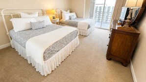 A hotel room with two beds, a wooden dresser, a mirror, and a view of the city through the window. - North Hampton Oceanfront 1501 (Myrtle Beach)