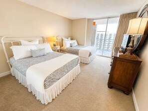 Ein Hotelzimmer mit zwei Betten, einem Holzschrank, einem Spiegel und Blick auf die Stadt durch das Fenster.
