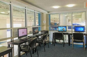 Ein Computerraum mit mehreren Arbeitsstationen, jeweils ausgestattet mit einem Bildschirm, einer Tastatur und einem Stuhl.