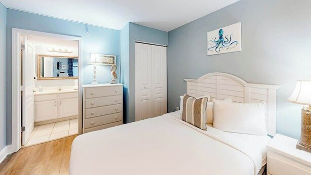 A bedroom with a bed, dresser, and a door. - Bay Watch Resort 0617 (North Myrtle Beach)