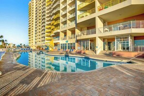 A hotel with a swimming pool, multiple balconies, and a brick-paved deck. - Bay Watch Resort 0617 (North Myrtle Beach)