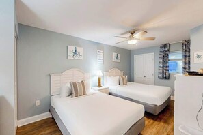 Ein Schlafzimmer mit zwei Betten, einem Deckenventilator und Kunstwerken an den Wänden.