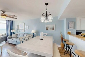 A modern living room with a dining area, a ceiling fan, and a kitchen with bar stools. - Bay Watch Resort 0617 (North Myrtle Beach)