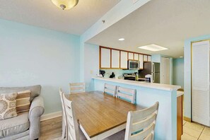 A compact living space with a dining area, kitchenette, and a sofa. - Roxanne Towers Unit 1101 (Myrtle Beach)