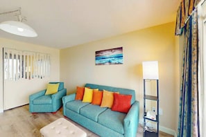 A living room with a teal sofa, a matching armchair, and a floor lamp. - Bay Watch Resort 0834 (North Myrtle Beach)