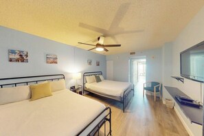 A hotel room with two beds, a ceiling fan, artwork on the walls, a TV, and a desk. - Bay Watch Resort 0834 (North Myrtle Beach)