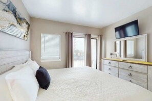 A hotel room with a bed, a dresser, a television, and a window with curtains. - Palace Resort Unit 108 (Myrtle Beach)