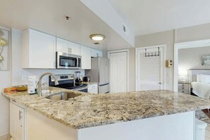 A modern kitchen with white cabinetry, a granite countertop, stainless steel appliances, and a built-in oven. - Palace Resort Unit 108 (Myrtle Beach)