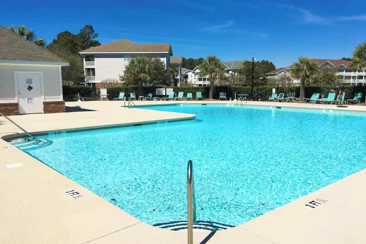 A swimming pool with lounge chairs and a building in the background.