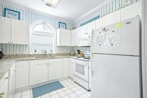 A kitchen with white cabinets, a stove, and a refrigerator. - Barefoot Sun & Golfing Fun (North Myrtle Beach)