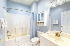 A bathroom with a bathtub, toilet, sink, and mirror. - Barefoot Sun & Golfing Fun (North Myrtle Beach)