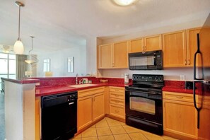 A kitchen with wooden cabinets, a black stove, a microwave, and a dishwasher. - Prince Resort Unit 1708 (North Myrtle Beach)
