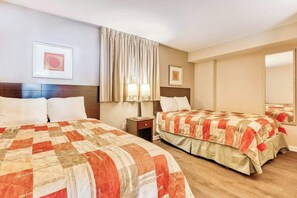 Ein Hotelzimmer mit zwei Betten, einem Nachttisch und einem Fenster mit Vorhängen.