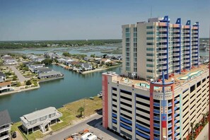 A high-rise hotel with multiple balconies, a swimming pool, and a marina in the background. - Prince Resort Unit 1708 (North Myrtle Beach)