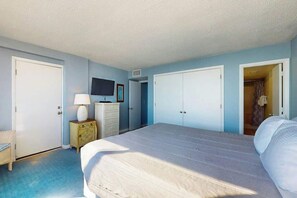 A bedroom with a bed, a dresser, a television, and a wardrobe. - Carolina Dunes Unit 603 (Myrtle Beach)