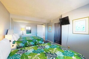 Ein Hotelzimmer mit zwei Betten, einem Fernseher und einem Vorhangfenster.