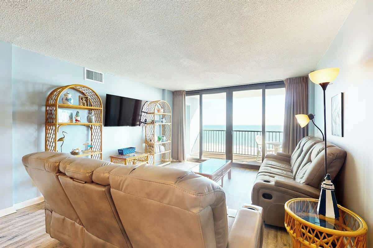 Una sala de estar moderna con un sofá, un televisor y un balcón con vistas.
