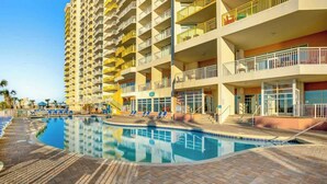 A hotel with a swimming pool, multiple balconies, and a brick-paved area. - Bay Watch Resort 0808 (North Myrtle Beach)