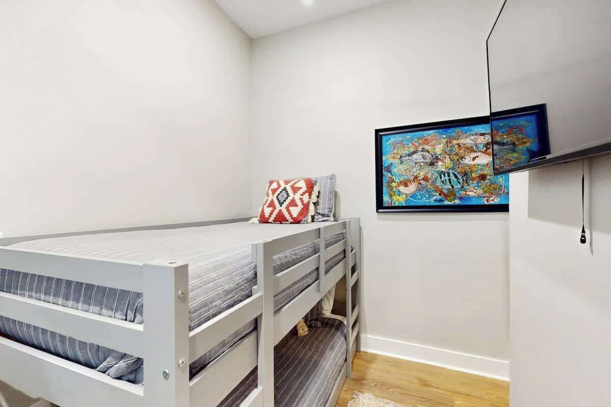 Une chambre avec un lit superposé, un tableau encadré au mur et une prise de courant.
