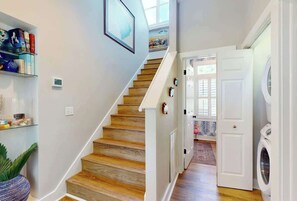 Eine Treppe führt zu einem Waschraum mit einer Waschmaschine und einer Tür zu einem weiteren Zimmer.