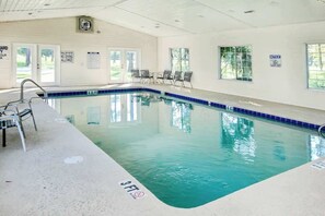 Une piscine intérieure dont la profondeur est indiquée par un repère à 3 pieds, dotée de panneaux de signalisation de sécurité et offrant une vue dégagée sur les environs.