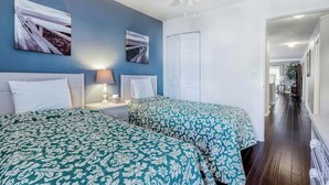 Ein Hotelzimmer mit zwei Betten, einem Deckenventilator und Bildern an den Wänden.