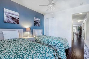 Ein Hotelzimmer mit zwei Betten, einem Deckenventilator und Bildern an den Wänden.