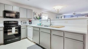 Eine moderne Küche mit Edelstahlgeräten, weißen Schränken und einer grauen Arbeitsplatte.