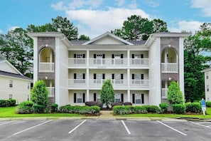 Ein mehrstöckiges Hotel mit Innenhof, Balkonen und Parkplatz.