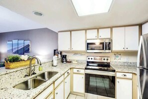 A modern kitchen with a built-in oven, stainless steel sink, and a microwave. - Bay Watch Resort 0933 (North Myrtle Beach)