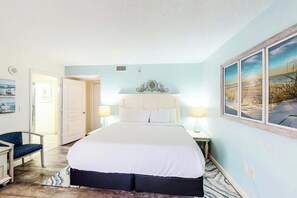 A bedroom with a bed, bedside lamps, a chair, and a painting on the wall. - Bay Watch Resort 0933 (North Myrtle Beach)