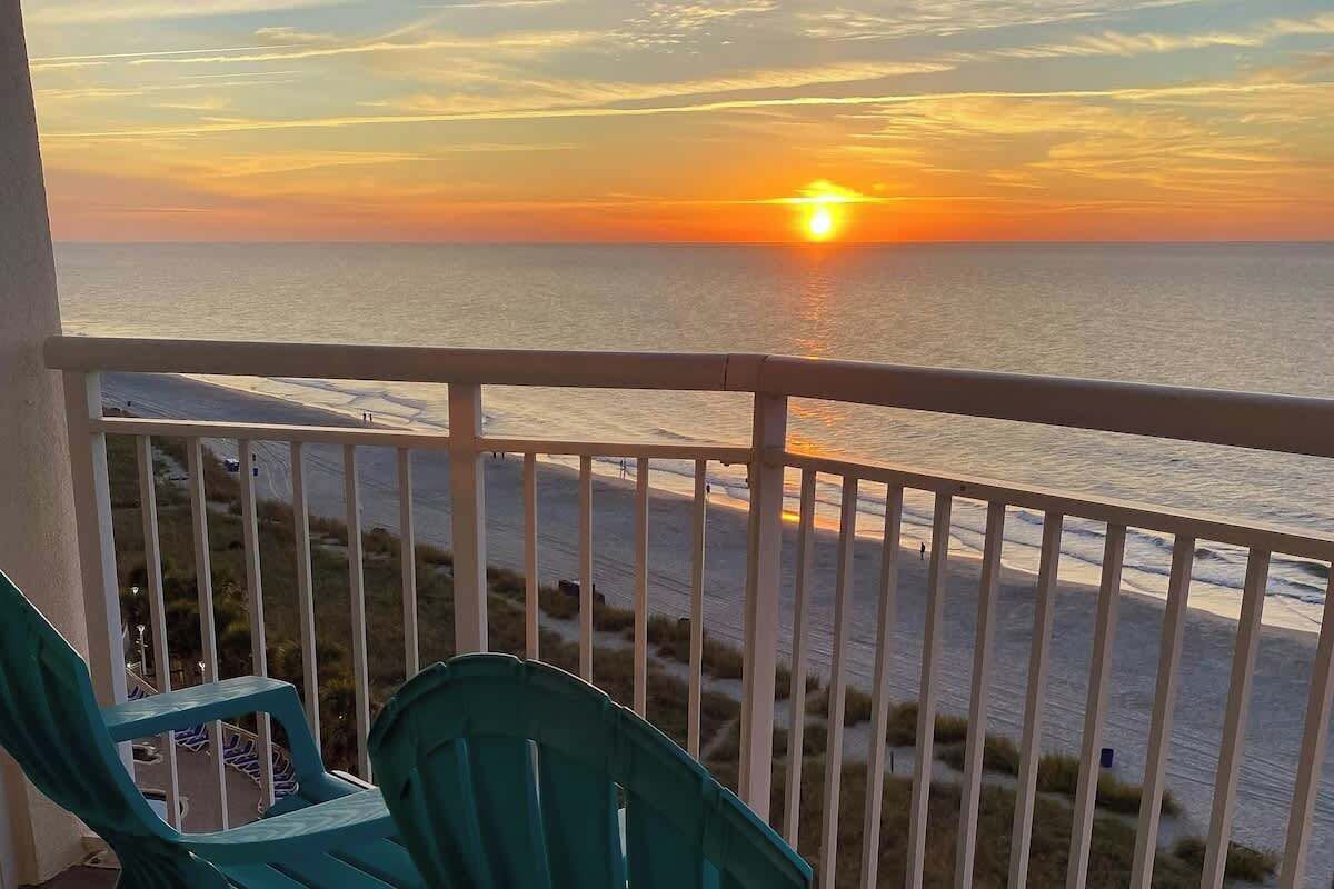 A balcony with a view of the ocean during sunset.