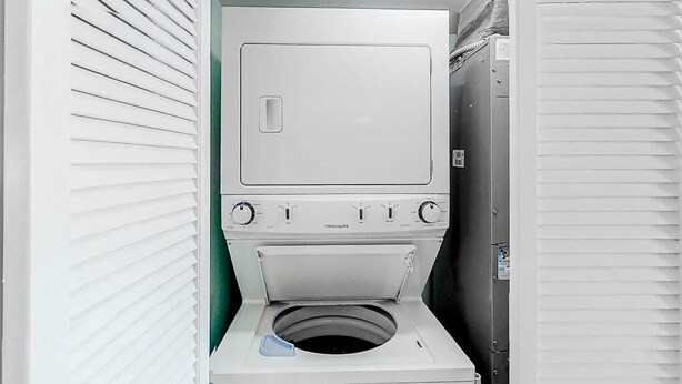Uma lavanderia compacta e branca, com máquina de lavar de abertura frontal e secadora.