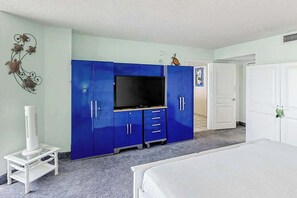 Ein Schlafzimmer mit einem Bett, einem Fernseher, einem Kleiderschrank und einem kleinen Tisch mit einem Heizgerät.
