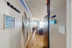 Ein Flur mit Holzboden, Deckenventilator und einem Schild mit der Aufschrift 'Zuhause ist dort, wo die Wellen brechen'.