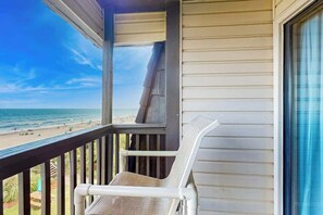 Ein Balkon mit Blick auf Strand und Meer.