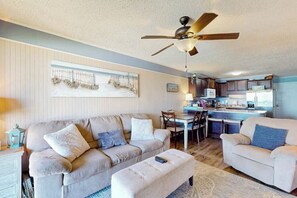Ein Wohnzimmer mit einer Couch, einem Hocker und einem Deckenventilator.