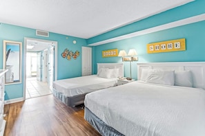 A bedroom with two beds, a bathroom, and a hallway. - Bay Watch Resort 0504 (North Myrtle Beach)