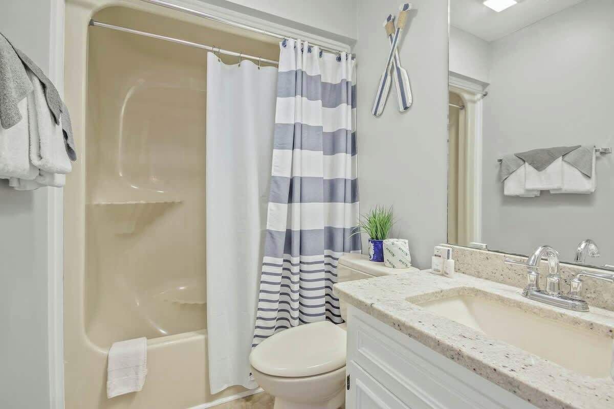A bathroom with a bathtub, toilet, and a sink with a mirror.